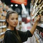 Foto de mulher pegando produto na prateleira de supermercado