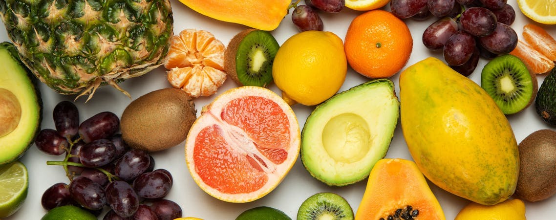 Foto de frutas laranja fatiada, mamão, abacate, uvas e frutas redondas verdes 
