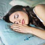 Foto de mulher dormindo com um travesseiro azul