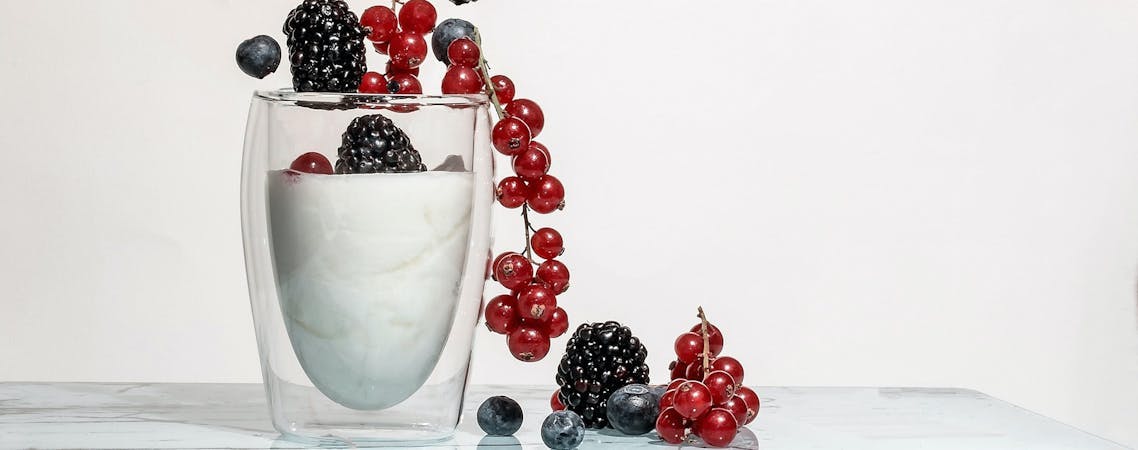 Foto de frutas vermelhas e pretas no copo de vidro com leite