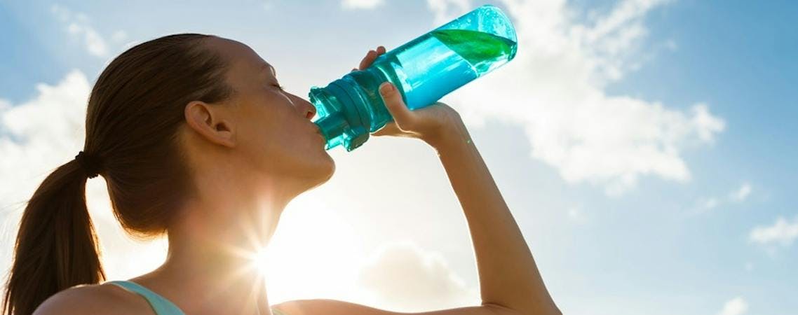 Mulher bebendo água no sol