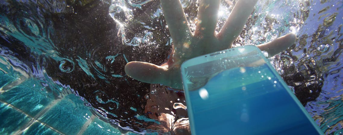 Foto de um celular caindo na piscina